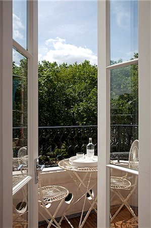 simsearch:845-05838374,k - View out of the window to mature trees of the park. Table and chairs on a small terrace. Stock Photo - Rights-Managed, Code: 845-08939643