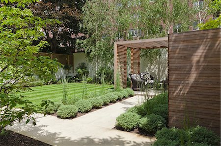 private garden - Slatted cedar pavilion on the right side of the lawn on the upper level of the garden. Silver birches along the boundary wall to the rear. sawn sandstone path lined with hebe and grasses. Architects: Modular Stock Photo - Rights-Managed, Code: 845-03777656