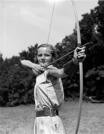 1930s GIRL WEARING A CAMP JUMPER WITH WIDE LEATHER BELT ABOUT TO RELEASE AN ARROW FROM BOW Stock Photo - Rights-Managed, Code: 846-05645852