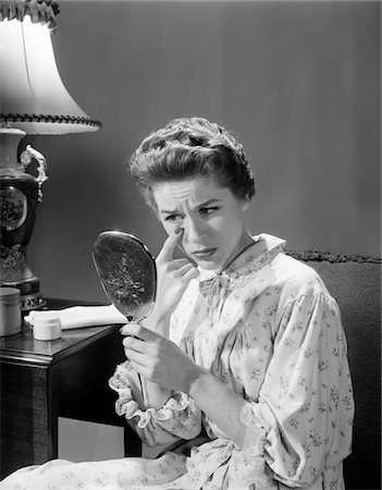 simsearch:846-05647696,k - 1950s - 1960s WOMAN IN NIGHTGOWN HOLDING MIRROR LOOK AT EYE WRINKLES AGING BEAUTY COSMETIC SERIOUS CONCERNED EXPRESSION Stock Photo - Rights-Managed, Code: 846-05645872