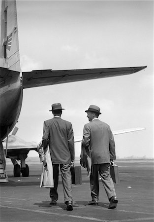 simsearch:846-05648112,k - 1950s TWO MEN BUSINESSMEN WEARING HATS CARRYING OVERCOATS AND BRIEFCASES WALKING TOGETHER TO BOARD PROPELLER AIRLINER Stock Photo - Rights-Managed, Code: 846-05645880