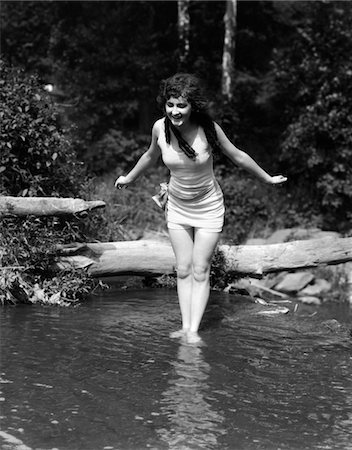 1920s LONG-HAIRED WOMAN IN OLD FASHION BATHING SUIT STANDING IN POND WITH FEET IN WATER ABOUT TO DIVE OUTDOOR Stock Photo - Rights-Managed, Code: 846-05645969