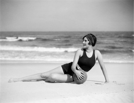 1920s WOMAN IN BATHING SUIT STRETCHED OUT ON BEACH IN FRONT OF WATER HOLDING BALL Stock Photo - Rights-Managed, Code: 846-05646077