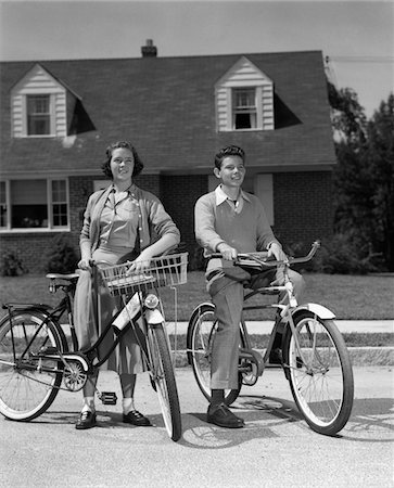 simsearch:846-02793798,k - 1950s SMILING TEENS ON SUBURBAN STREET BOY SITTING ON BIKE GIRL STANDING BESIDE BIKE WITH BASKET Stock Photo - Rights-Managed, Code: 846-05646091