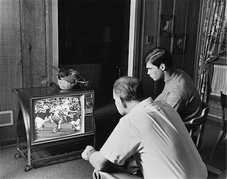 1960s - 1970s TEEN BOY WATCHING FOOTBALL GAME ON TELEVISION WITH ADULT DAD Foto de stock - Con derechos protegidos, Código: 846-05646507