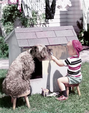 1950s LITTLE BOY RED BALL CAP PAINTING SIDE DOGHOUSE DOG KERRY BLUE TERRIER SITTING ON STOOL WATCHING Stock Photo - Rights-Managed, Code: 846-05646821