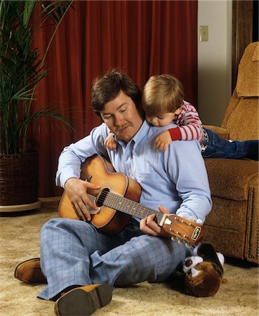 father and son vintage - 1980s FATHER PLAYING GUITAR SITTING ON FLOOR SON LISTENING LEANING ON HIS SHOULDERS Stock Photo - Rights-Managed, Code: 846-05647249