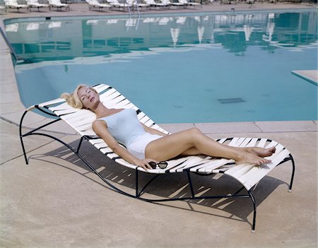 1960s ELEGANT TALL BLOND WOMAN IN BATHING SUIT RECLINING ON A LOUNGE CHAIR BY SWIMMING POOL TANNING IN THE SUNSHINE Stock Photo - Rights-Managed, Code: 846-05647481
