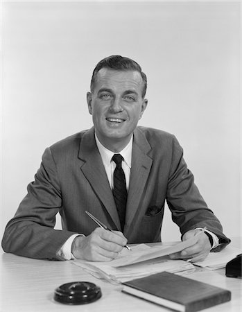 simsearch:846-02795767,k - 1960s SMILING HAPPY BUSINESSMAN PEN IN HAND SIGNING PAPERS AT DESK Stock Photo - Rights-Managed, Code: 846-05647730