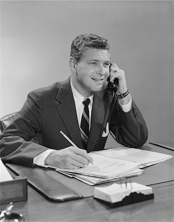 simsearch:846-02796457,k - 1960s BUSINESSMAN SEATED AT DESK TALKING ON TELEPHONE SMILING WRITING WITH PENCIL Stock Photo - Rights-Managed, Code: 846-05647732