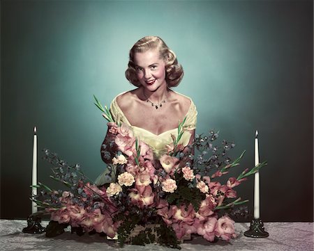1950s SMILING WOMAN WEARING FORMAL GOWN ARRANGING FLOWERS CENTERPIECE ON DINING TABLE Stock Photo - Rights-Managed, Code: 846-05647846
