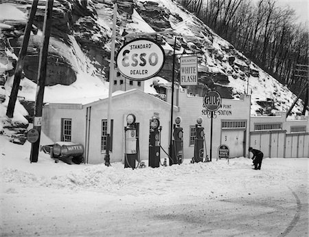simsearch:6105-05395912,k - 1940s SERVICE STATION IN MOUNTAINS IN WINTER SEVERAL GAS PUMPS GARAGES & OIL & GAS SIGNS Stock Photo - Rights-Managed, Code: 846-05648038
