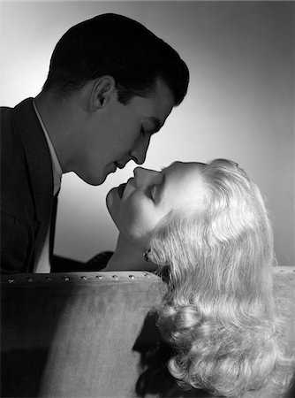 simsearch:846-05646032,k - 1940s - 1950s MOVIE STAR STUDIO STYLE ROMANTIC COUPLE EMBRACING ON SOFA ABOUT TO KISS HUSBAND SILHOUETTE WIFE LONG BLOND HAIR Stock Photo - Rights-Managed, Code: 846-05648045