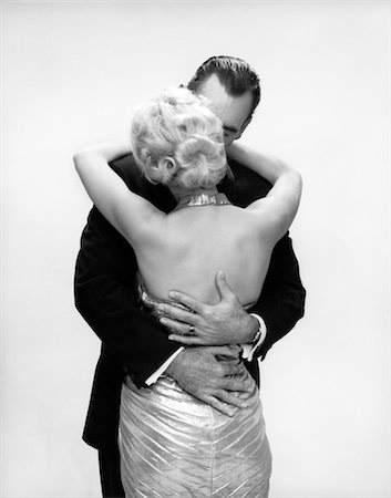 simsearch:846-05646226,k - 1950s - 1960s KISSING COUPLE BLOND WOMAN BACKLESS SATIN EVENING DRESS MAN EMBRACING FROM BEHIND Stock Photo - Rights-Managed, Code: 846-05648081
