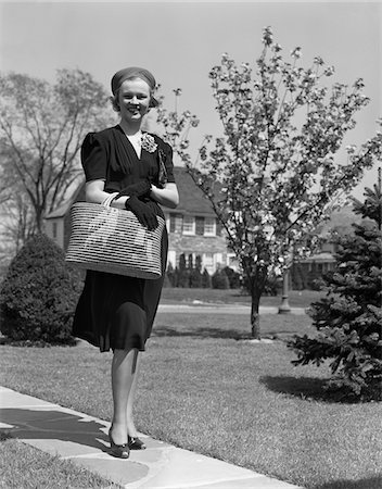 simsearch:846-08030416,k - 1930s - 1940s STYLISHLY DRESSED WOMAN WALKING DOWN SUBURBAN STREET CARRYING STRAW BAG Stock Photo - Rights-Managed, Code: 846-05648150