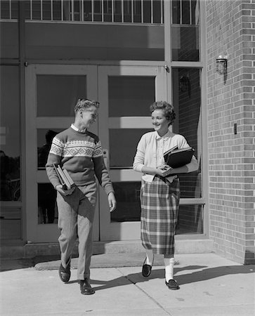 simsearch:846-02793798,k - 1950s TWO TEENAGE STUDENTS BOY AND GIRL WALKING AWAY FROM SCHOOL DOORS CARRYING BOOKS Stock Photo - Rights-Managed, Code: 846-05648178