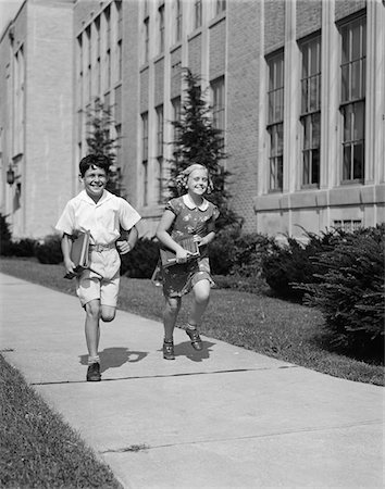 simsearch:846-02793798,k - 1940s BOY GIRL RUNNING DOWN SIDEWALK CARRYING SCHOOL BOOKS SMILING Stock Photo - Rights-Managed, Code: 846-05648289