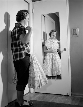 simsearch:846-08140107,k - 1950s TEEN GIRL IN JEANS HOLDING FORMAL DRESS UP TO CHEST LOOKING IN MIRROR ON BACK OF BEDROOM DOOR Stock Photo - Rights-Managed, Code: 846-05648387