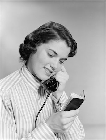 1950s YOUNG WOMAN TALKING ON TELEPHONE READING ADDRESS FROM LITTLE BLACK BOOK Stock Photo - Rights-Managed, Code: 846-05648503