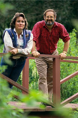 romantic old fashioned women clothes - 1980s COUPLE SMILING LEANING ON WOODEN BRIDGE IN GARDEN LOOKING AT CAMERA Stock Photo - Rights-Managed, Code: 846-06111730