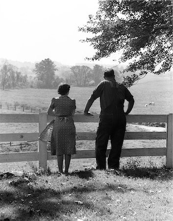 1940s REAR VIEW OF ELDERLY FARM COUPLE STANDING AT FENCE LOOKING OUT ONTO PASTURE Stock Photo - Rights-Managed, Code: 846-06111787