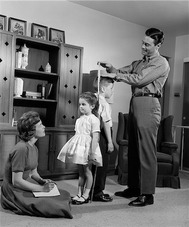 simsearch:846-09012864,k - 1960s FATHER MEASURING DAUGHTER & SON BACK-TO-BACK WITH MOTHER RECORDING INFORMATION Stock Photo - Rights-Managed, Code: 846-06111925