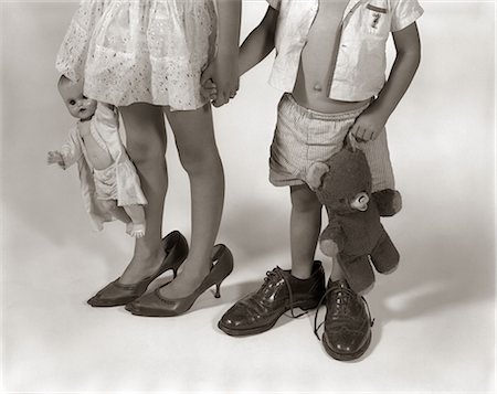 1950s 1960s CLOSE-UP OF LITTLE GIRL & BOY FROM NECK DOWN WEARING PARENTS' SHOES Foto de stock - Con derechos protegidos, Código: 846-06111921