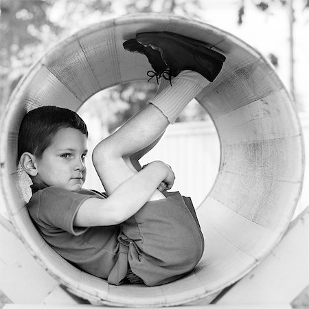 playground retro - 1970s SIDE VIEW OF BOY SCRUNCHED UP INSIDE TUBE HOLDING KNEES TO CHEST Stock Photo - Rights-Managed, Code: 846-06111934