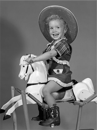 1950s GIRL DRESSED AS COWGIRL RIDING ROCKING HORSE Stock Photo - Rights-Managed, Code: 846-06111937