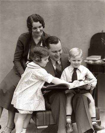 simsearch:846-02795935,k - 1930s FATHER READING BOOK TO DAUGHTER & SON WITH MOTHER LOOKING OVER HIS SHOULDER Stock Photo - Rights-Managed, Code: 846-06111963