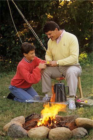 retro fishing - 1990s FATHER AND SON BY CAMPFIRE WORKING ON FISHING ROD AND FLIES Stock Photo - Rights-Managed, Code: 846-06112014