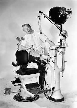 simsearch:846-05645854,k - 1950s MAN DENTIST HOLDING GLASSES SPEAKING FOOT PROPPED UP ON DENTAL CHAIR AND EQUIPMENT LOOKING AT CAMERA Stock Photo - Rights-Managed, Code: 846-06112172