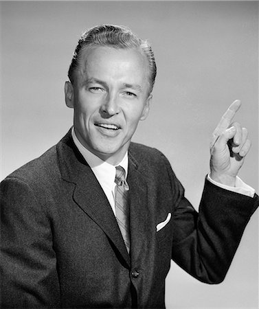simsearch:846-05648290,k - 1950s BUSINESS MAN POINTING WITH LEFT HAND QUIZZICAL EXPRESSION LOOKING AT CAMERA Stock Photo - Rights-Managed, Code: 846-06112268