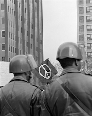 simsearch:846-02796457,k - 1970s BACK VIEW OF TWO POLICEMAN IN HELMETS AT DEMONSTRATION WITH PEACE SIGN IN BACKGROUND FRAMED BETWEEN THEIR HEADS Stock Photo - Rights-Managed, Code: 846-06112284
