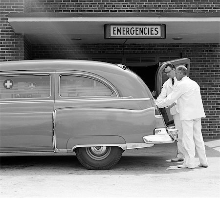 1950s TWO AMBULANCE DRIVERS EMTS DOCTORS AT REAR OF AMBULANCE AT HOSPITAL EMERGENCY ROOM ENTRANCE Foto de stock - Con derechos protegidos, Código: 846-07760754