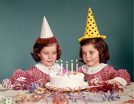 1960s TWIN GIRLS WEARING PARTY HATS AND BIRTHDAY CAKE WITH FIVE CANDLES Stock Photo - Rights-Managed, Code: 846-08030396