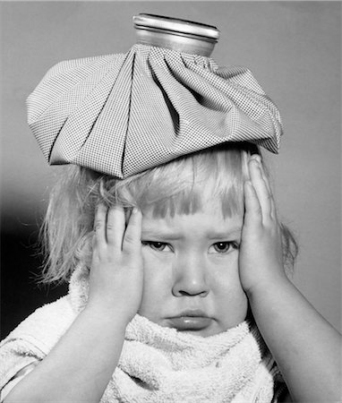 1950s UNHAPPY LITTLE BLONDE GIRL ICE PACK ON HEAD HANDS SIDE OF FACE TOWEL WRAPPED AROUND NECK FEVER HEADACHE SORE THROAT MUMPS Stock Photo - Rights-Managed, Code: 846-08512677