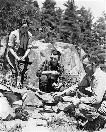 simsearch:846-02793254,k - 1930s TWO MEN ONE WOMAN HOLDING SKILLET SITTING CROUCHING AROUND CAMPFIRE COOKING A MEAL LAKE OF THE WOODS ONTARIO CANADA Photographie de stock - Rights-Managed, Code: 846-09012718
