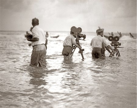 simsearch:846-05645898,k - 1920s FILMMAKERS IN KNEE DEEP WATER OCEAN SHOOTING FILMING CAMERAS Stock Photo - Rights-Managed, Code: 846-09012733