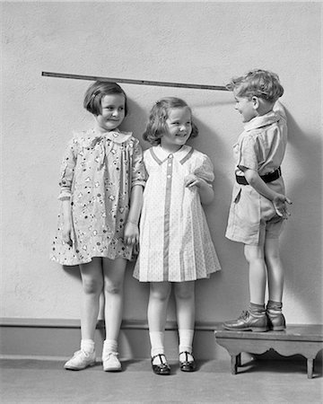 simsearch:846-07200088,k - 1930s BOY STANDING ON A STOOL MEASURING THE HEIGHT OF TWO GIRLS WITH YARD STICK Stock Photo - Rights-Managed, Code: 846-09012800