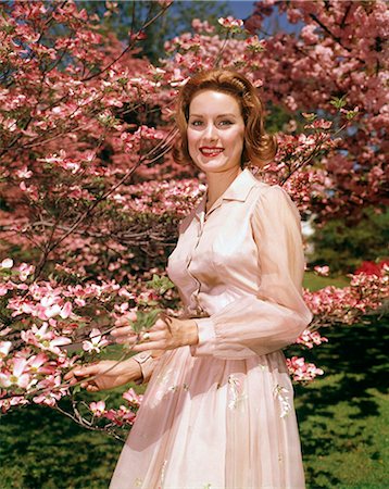 simsearch:846-08140107,k - 1950s 1960s YOUNG RED HAIRED WOMAN POSING UNDER BLOSSOMING DOGWOOD TREE LOOKING AT CAMERA Stock Photo - Rights-Managed, Code: 846-09012832