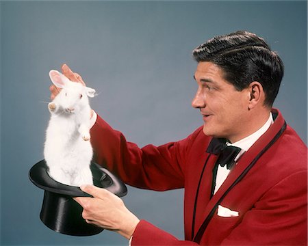 simsearch:846-05645665,k - 1960s 1970s MAN MAGICIAN WEARING RED SUIT PULLING WHITE RABBIT OUT OF TOP HAT Stock Photo - Rights-Managed, Code: 846-09012859