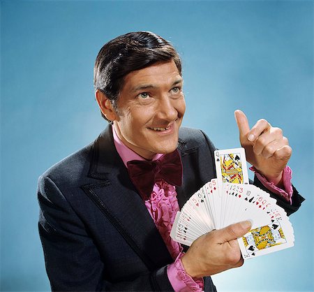 simsearch:846-07200088,k - 1960s 1970s SMILING MAN MAGICIAN HOLD FANNED OUT DECK OF CARDS POINTING AT QUEEN OF SPADES RAISED Stock Photo - Rights-Managed, Code: 846-09012867