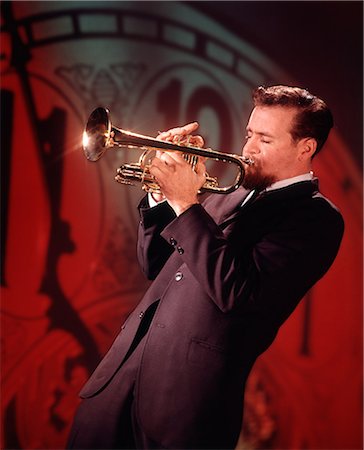 1960s MAN JAZZ MUSICIAN PLAYING TRUMPET NEAR MIDNIGHT NEW YEARS CLOCK FACE IN BACKGROUND Photographie de stock - Rights-Managed, Code: 846-09012952