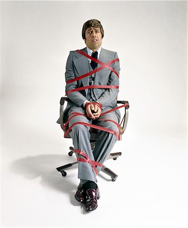 simsearch:846-02792220,k - 1970s BUSINESS MAN TIED UP IN RED TAPE SITTING IN OFFICE SWIVEL CHAIR Stock Photo - Rights-Managed, Code: 846-09013000