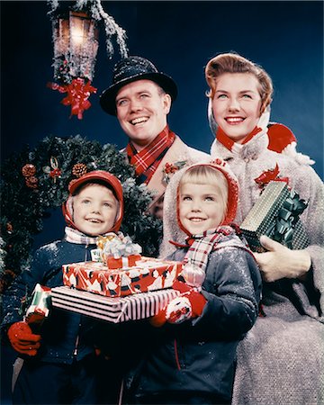 father christmas family portrait - 1950s FAMILY MAN WOMAN TWO KIDS HOLDING CHRISTMAS PRESENTS SMILING STANDING BENEATH LANTERN Stock Photo - Rights-Managed, Code: 846-09013054
