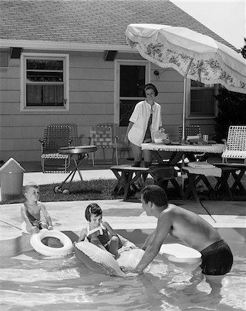 simsearch:846-05648202,k - 1960s FAMILY OF FOUR AROUND BACKYARD SWIMMING POOL MOTHER AT UMBRELLA TABLE ON PATIO FATHER SON DAUGHTER IN POOL SUMMER Stock Photo - Rights-Managed, Code: 846-09013113