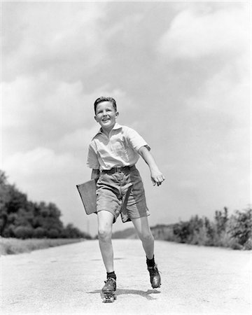 simsearch:846-02793798,k - 1930s 1930s SMILING BOY ROLLER SKATING TO SCHOOL LOOKING AT CAMERA CARRYING TEXTBOOK BINDER Stock Photo - Rights-Managed, Code: 846-09013132