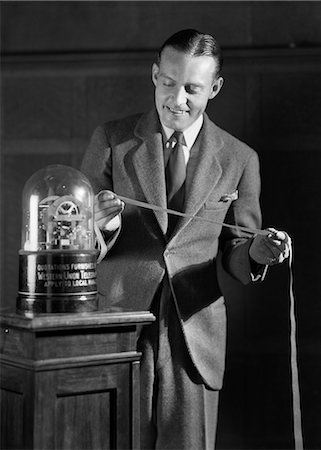 simsearch:846-08639518,k - 1920s 1930s SMILING MAN READING STOCK QUOTES AND PRICES ON TICKER TAPE MACHINE PAPER TAPE Stock Photo - Rights-Managed, Code: 846-09085253