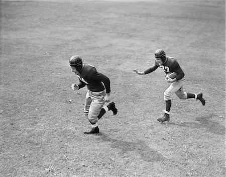 simsearch:846-05645898,k - 1940s TWO MEN PLAYING FOOTBALL WEARING LEATHER HELMETS ONE RUNNING WITH FOOTBALL OTHER BLOCKING FOR HIM Stock Photo - Rights-Managed, Code: 846-09085279